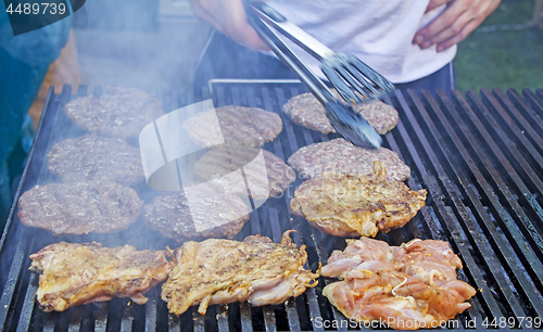 Image of Chef preparing burgers at the barbecue outdoors