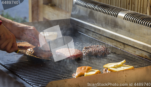 Image of Chef preparing burgers at the barbecue outdoors