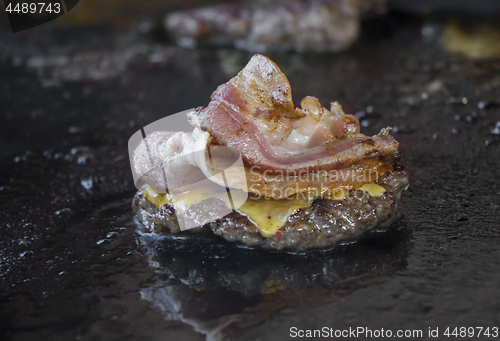 Image of Preparing burgers with bacon at the barbecue outdoors