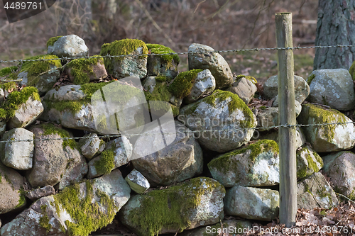 Image of Barbed wire by an old stone wall