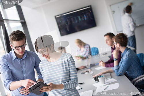 Image of Two Business People Working With Tablet in office