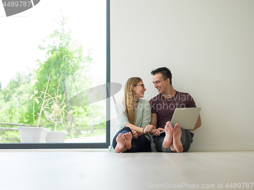 Image of couple using laptop on the floor at home