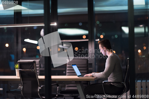 Image of man working on laptop in dark office