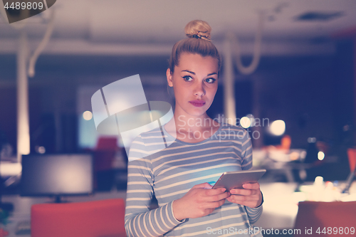 Image of woman working on digital tablet in night office