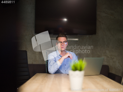 Image of man working on laptop in dark office