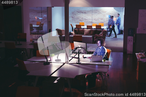 Image of man working on computer in dark office