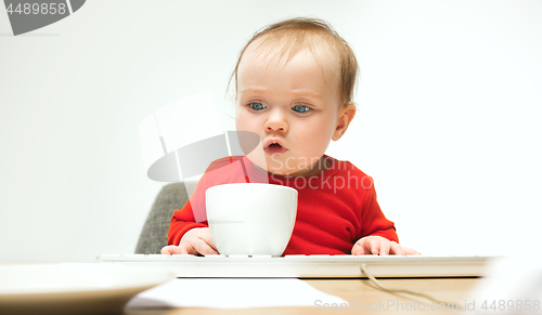 Image of Happy child baby girl toddler sitting with keyboard of computer isolated on a white background