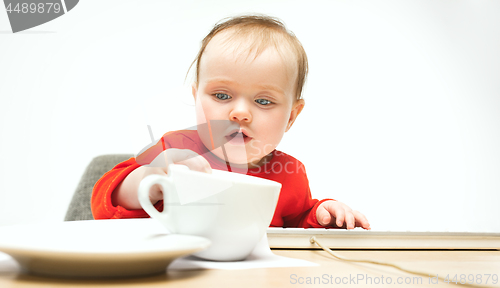 Image of Happy child baby girl toddler sitting with keyboard of computer isolated on a white background