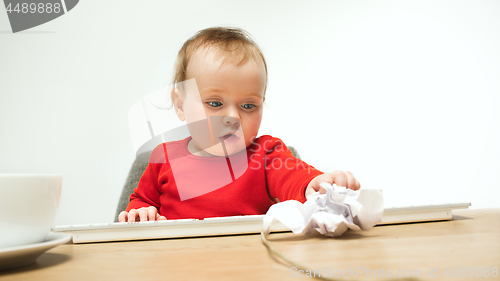 Image of Happy child baby girl toddler sitting with keyboard of computer isolated on a white background