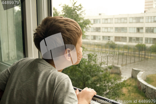 Image of Boy watching the rain through the window