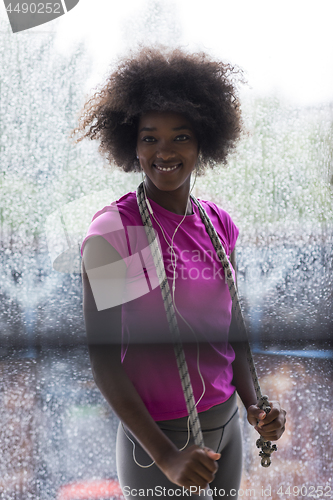 Image of portrait of young afro american woman in gym while listening mus