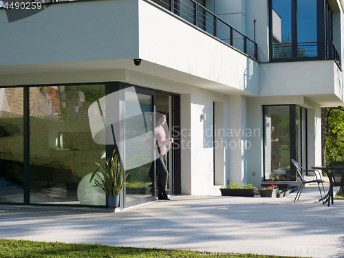 Image of man drinking coffee in front of her luxury home villa