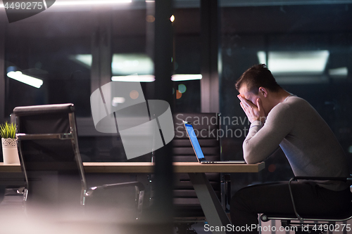 Image of man working on laptop in dark office