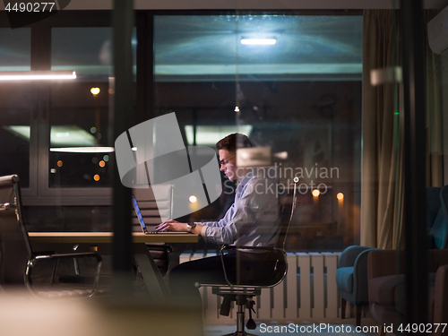 Image of man working on laptop in dark office