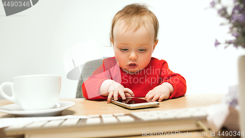 Image of Happy child baby girl toddler sitting with keyboard of computer isolated on a white background