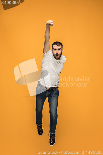 Image of Freedom in moving. handsome young man jumping against orange background