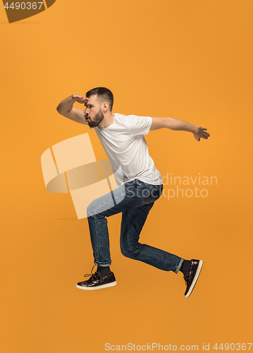 Image of Freedom in moving. handsome young man jumping against orange background