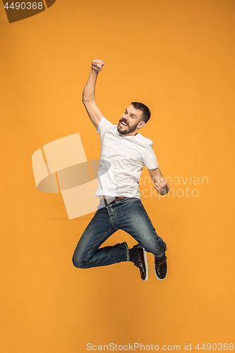 Image of Freedom in moving. handsome young man jumping against orange background