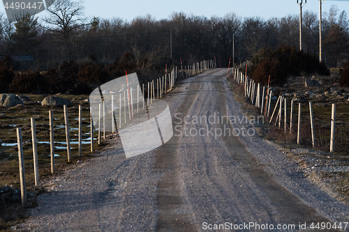Image of Gravel road with fence and snow stakes
