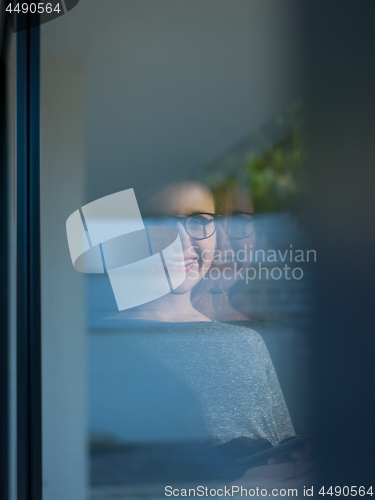 Image of Woman using tablet at home by the window