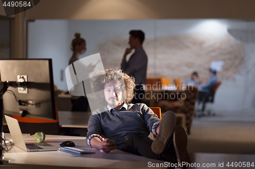 Image of businessman sitting with legs on desk at office