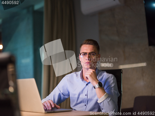 Image of man working on laptop in dark office