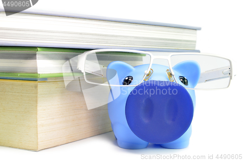 Image of Piggy bank, glasses and stack of books 