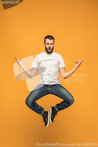 Image of Freedom in moving. handsome young man jumping against orange background