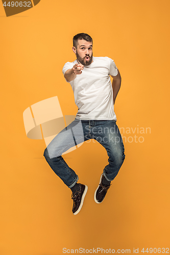 Image of Freedom in moving. handsome young man jumping against orange background