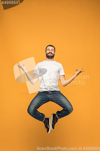 Image of Freedom in moving. handsome young man jumping against orange background