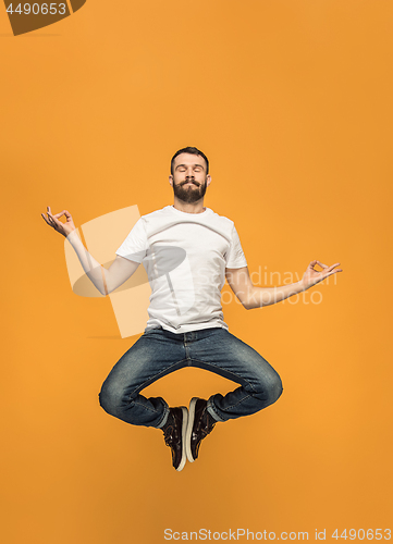 Image of Freedom in moving. handsome young man jumping against orange background