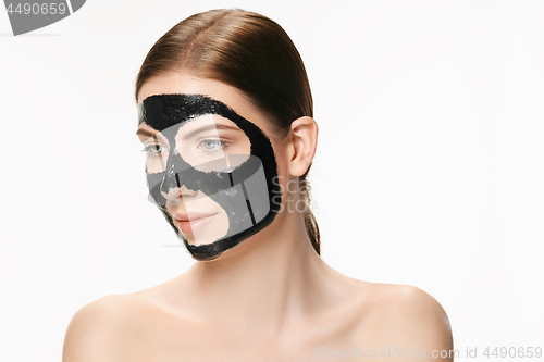 Image of Young beautiful woman applying a mask for the face of the therapeutic black mud. Spa treatment