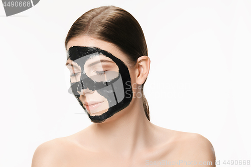 Image of Young beautiful woman applying a mask for the face of the therapeutic black mud. Spa treatment