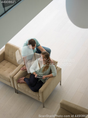 Image of couple relaxing at  home with tablet computers