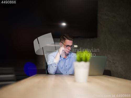 Image of man working on laptop in dark office