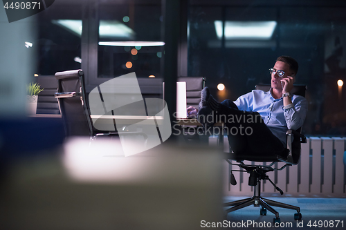 Image of businessman using mobile phone in dark office