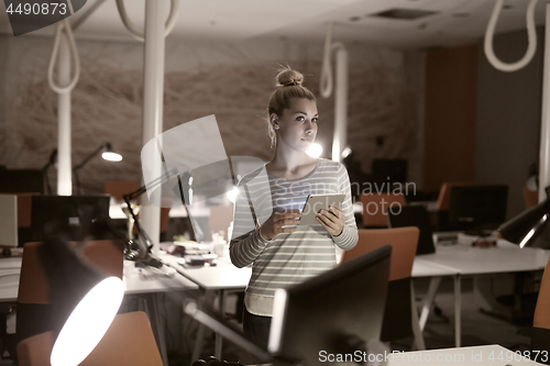 Image of woman working on digital tablet in night office