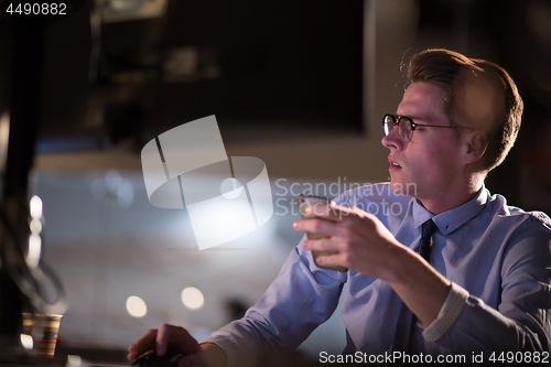 Image of man using mobile phone in dark office