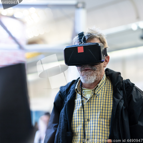 Image of Senior man wearing virtual reality goggles watching virtual reality presentation.