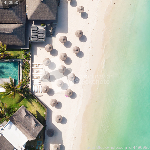 Image of Aerial view of amazing tropical white sandy beach with palm leaves umbrellas and turquoise sea, Mauritius.