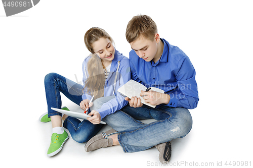 Image of Teen age boy and girl with tablet and notebook