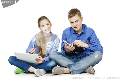 Image of Teen age boy and girl with tablet and notebook