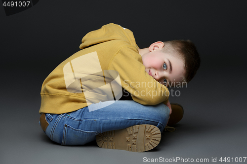 Image of Handsome little boy in jeans sitting on floor