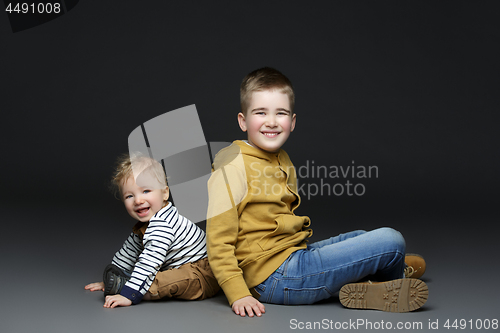 Image of Two brothers in jeans sitting on floor