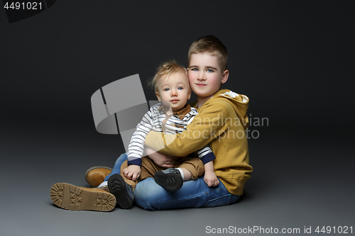 Image of Two brothers in jeans sitting on floor