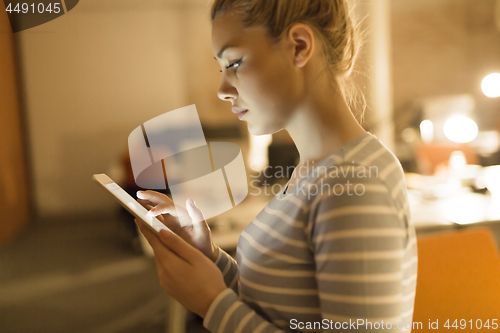 Image of woman working on digital tablet in night office