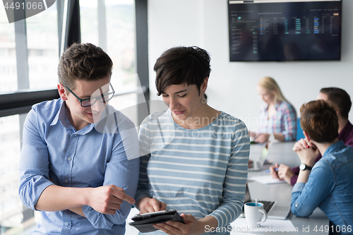 Image of Two Business People Working With Tablet in office