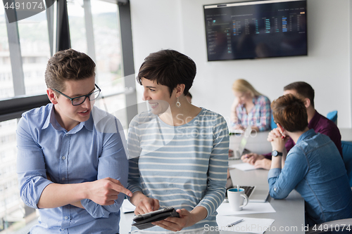 Image of Two Business People Working With Tablet in office