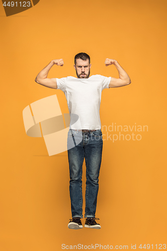 Image of Freedom in moving. handsome young man jumping against orange background
