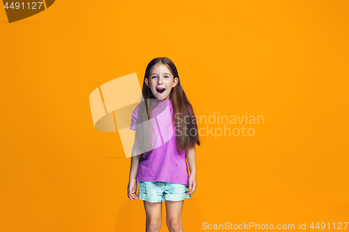 Image of The happy teen girl standing and smiling against orange background.